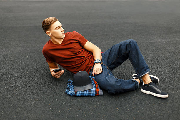 istock Handsome man with phone lying on the pavement and rests. 2232410527