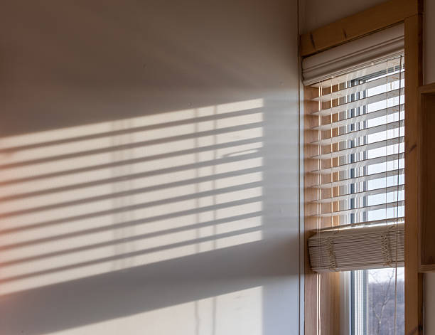 istock Sunlight Through Window Blinds Casting Shadows in Minimalist Home Interior 2232410742