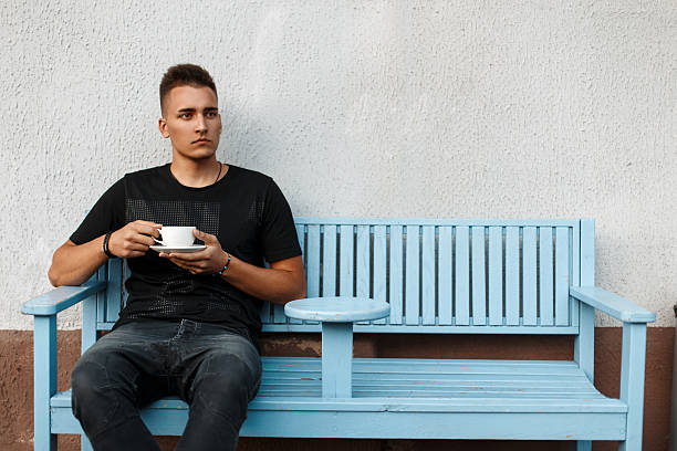 Handsome young man with coffee on a bench