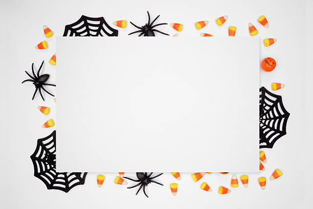 istock Halloween frame of scattered candy and decor surrounding white paper with copy space over a white background 2232414021