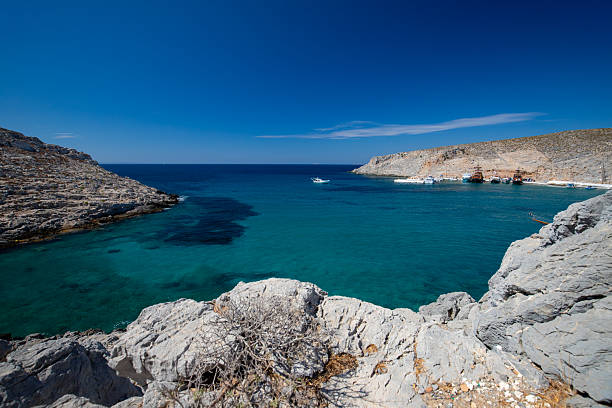 Seascape with rocky shoreline and distant mountains under a clear sky, Greek Islands