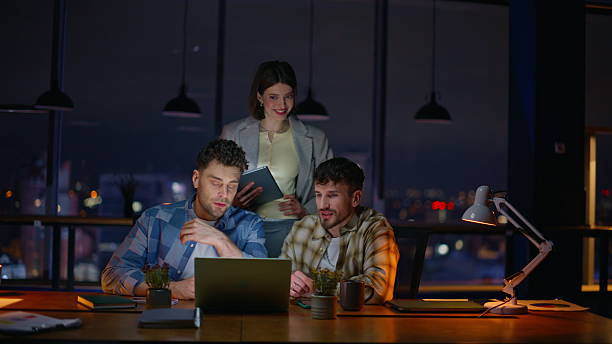 istock Late managers looking computer screen dark office. Overtime inspired colleagues 2232417764