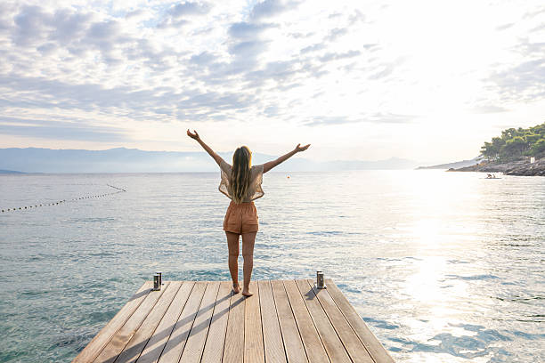 istock Woman Standing on Dock with Raised Arms 2232418605