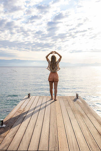 istock Woman Making Heart Shape on Pier at Sunrise 2232418723
