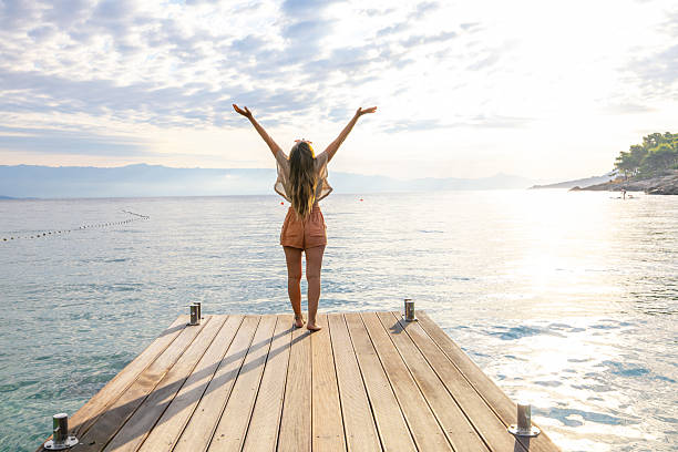 istock Woman Standing on Dock with Raised Arms 2232418726