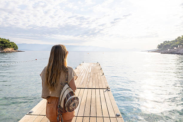 istock Woman Standing on Pier Overlooking Calm Sea 2232419593