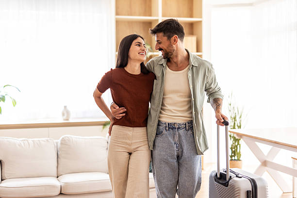 istock Happy couple leaving home for vacation with suitcase 2232419927