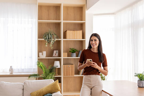 istock Young woman using smartphone at home in modern living room 2232421996