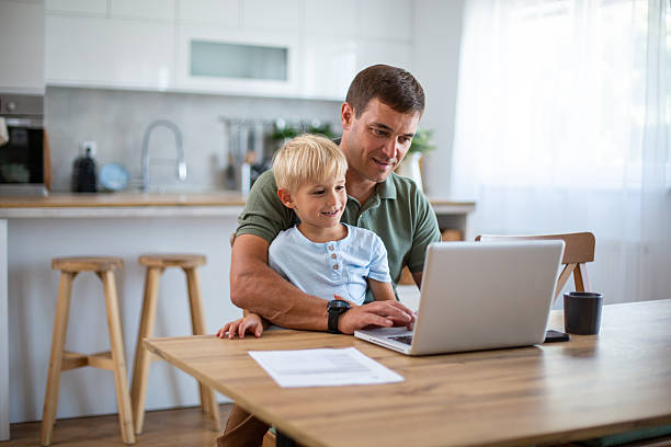 istock Father and son using laptop together in kitchen 2232429955
