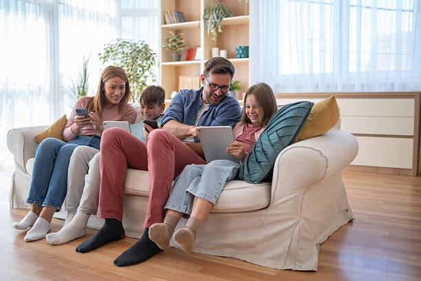 istock Family enjoying using electronic devices at home, sitting on the sofa 2232434894