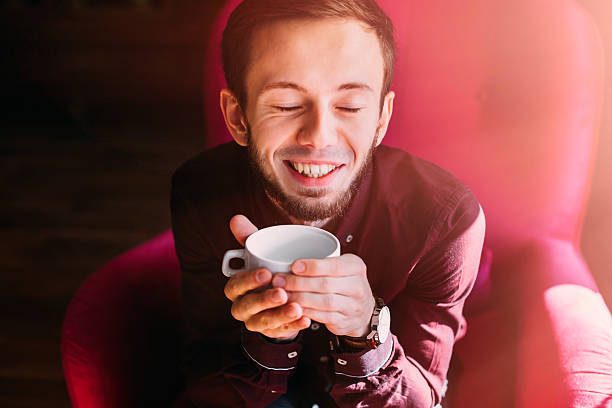 istock bearded guy sits in armchair, closes his eyes and holds a cup. h 2232435155