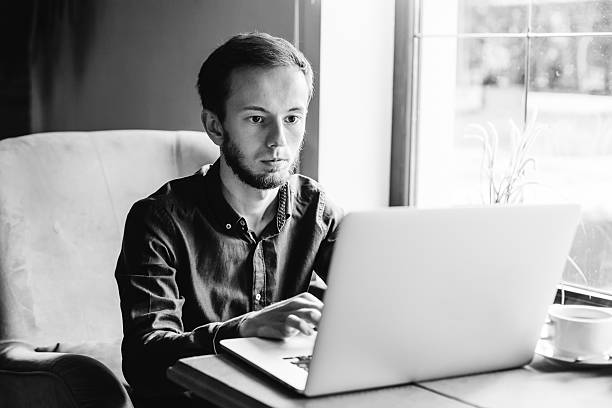 istock man with beard sitting on armchair with laptop computer and work 2232435169