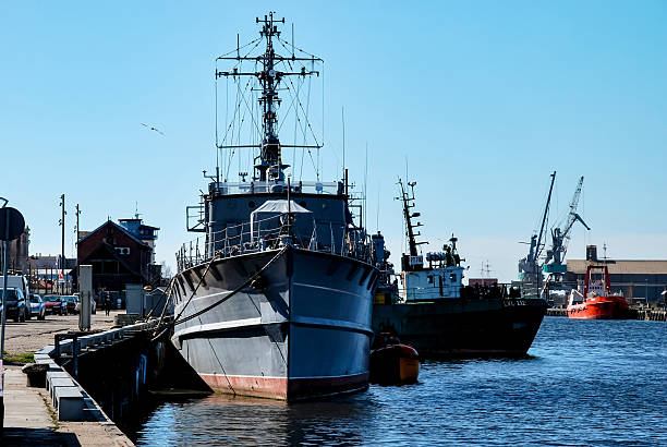 Liepaja, Latvia - May 04, 2013 - Three large ships docked at industrial harbor under clear blue sky.