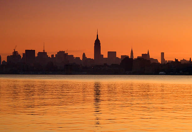 Lower Manhattan Skyline Silhouette at Sunrise with Water Reflection