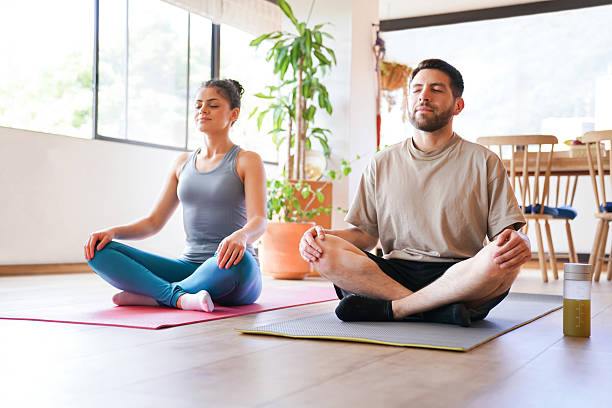istock Couple meditating together at home 2232443076