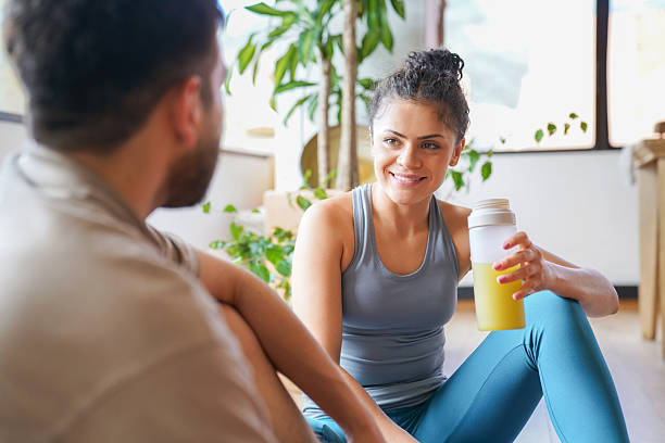 istock Woman drinking a green smoothie while talking to her personal trainer at home 2232443085