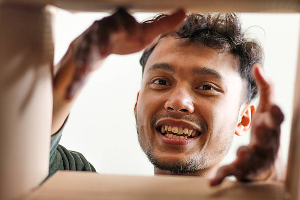 istock Excited Young Asian Man Smiling And Reaching Into Box 2232443535