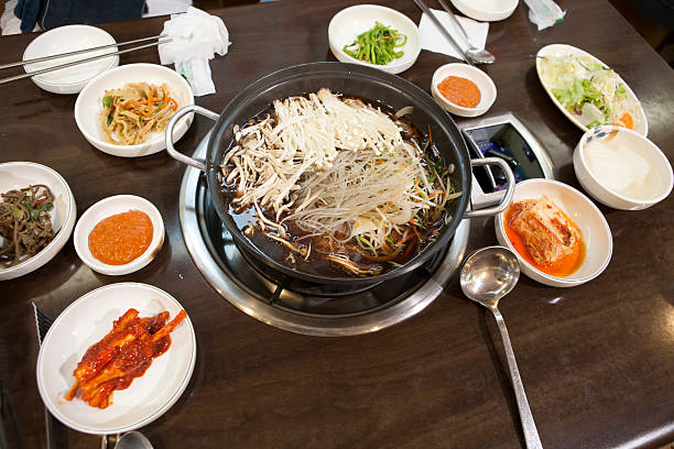 Asian woman hand holding medal chopsticks to eat appetiser dish in a Korean restaurant. Korean food traditional Kimchi