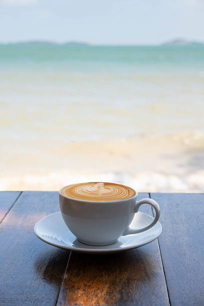 istock Hot coffee with latte art on table on sea background 2232444713