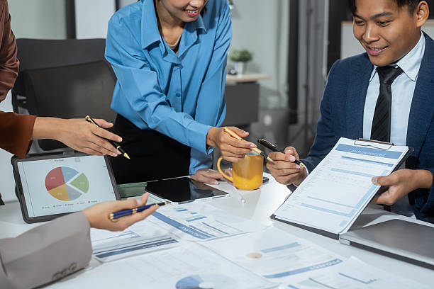 Entrepreneurs, marketers, managers, and financial analysts gather around the table to analyze data, present results, plan strategies, discuss efficiencies,grow their businesses through collaboration