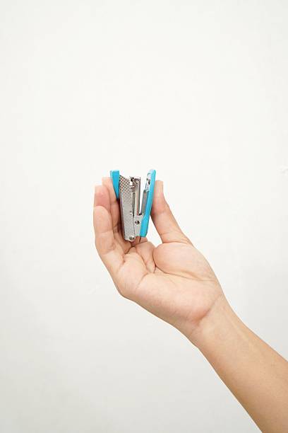 istock woman's hand holding a small blue stapler isolated on a white background 2232449103