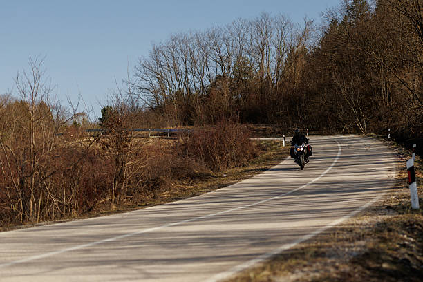 istock Young biker in leather suit driving his motorcycle through countryside 2232451442