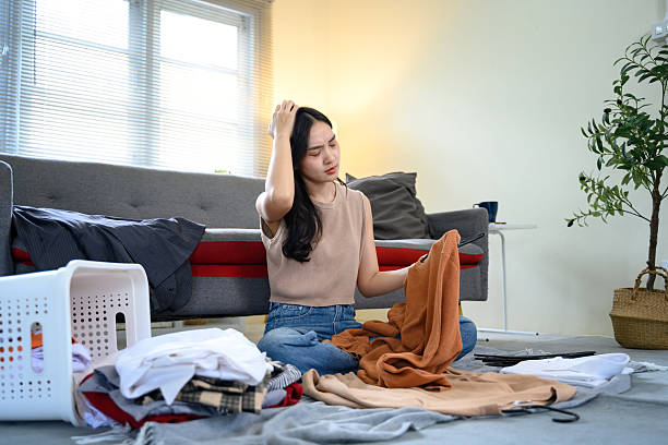 istock Tired female organizing messy laundry pile with frustrated expression 2232453251