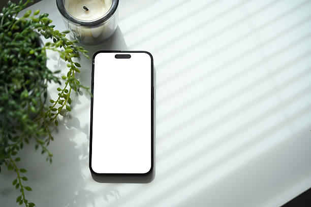 istock Smartphone with blank screen mockup placed on white desk with plant and candle 2232453314