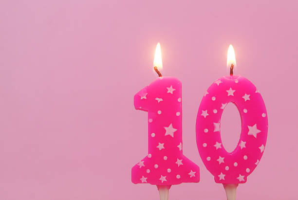 istock Burning pink birthday cake candles on pink background. Number 10. 2232458151
