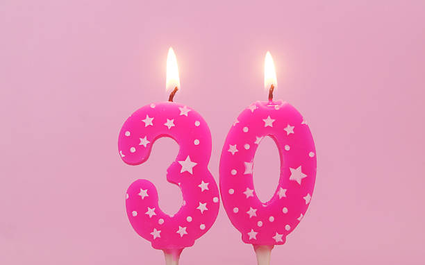 istock Burning pink birthday cake candles on pink background. Number 30. 2232458152