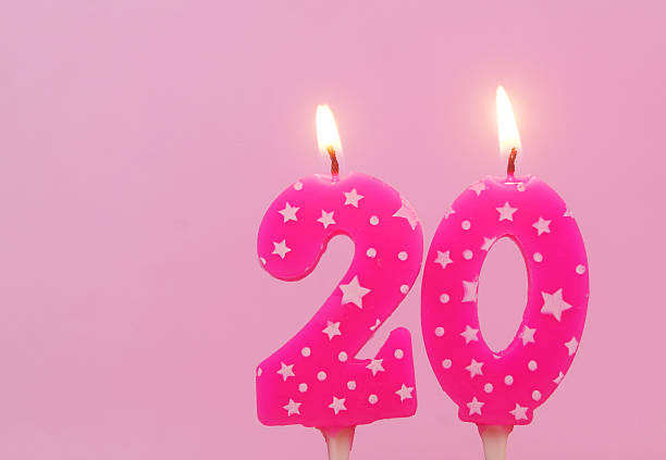 istock Burning pink birthday cake candles on pink background. Number 20. 2232458155