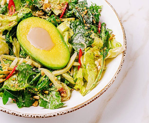 istock Fresh green salad with avocado and nuts served in a bowl 2232459605