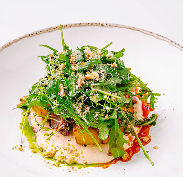 A vibrant salad features fresh arugula topped with seasonal vegetables and crushed nuts. Colorful dressings add visual appeal, creating a delightful dish ideal for a healthy meal.