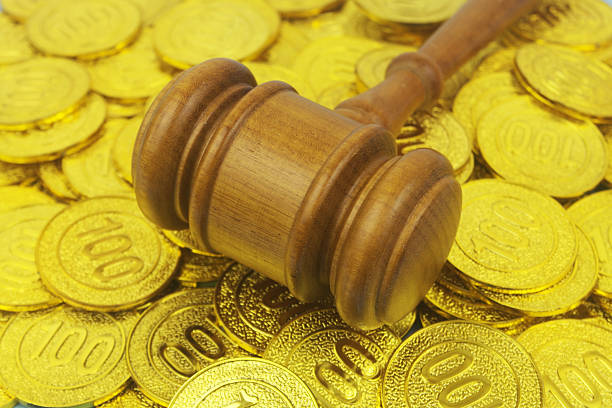 Close up of wooden judge gavel on gold coins