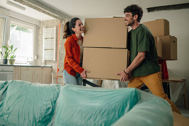 istock Young couple carrying boxes into new home, smiling and laughing 2232462219