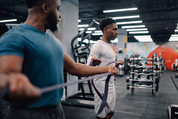 istock Two young men exercising with resistance band in gym 2232464360