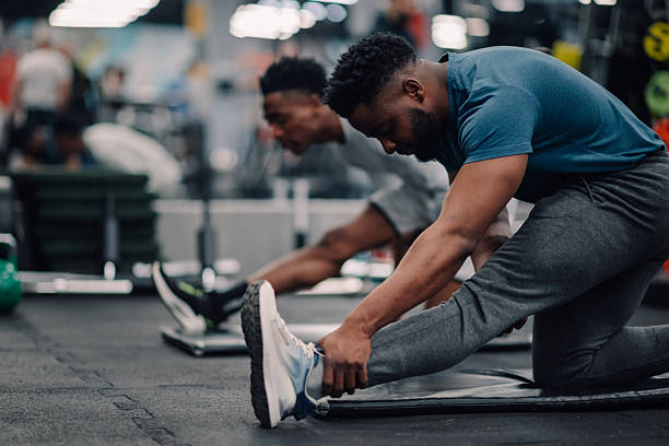A man with a handicapped hand doing shoulder stretching exercises in the gym. Young and determined man with disability preparing for a work out in a gym.
