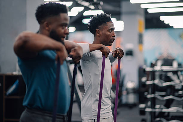 istock Two young men performing resistance band exercises in gym 2232464382