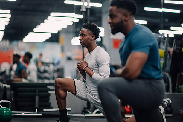 istock Two young men doing lunges in the gym during a fitness class 2232464384