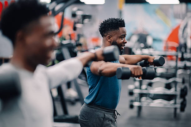 istock Two young men lifting weights during workout session in gym 2232464406
