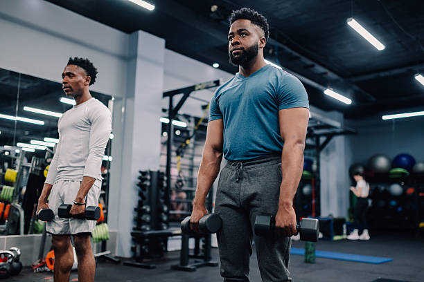 istock Two young men lifting weights in modern gym 2232464409