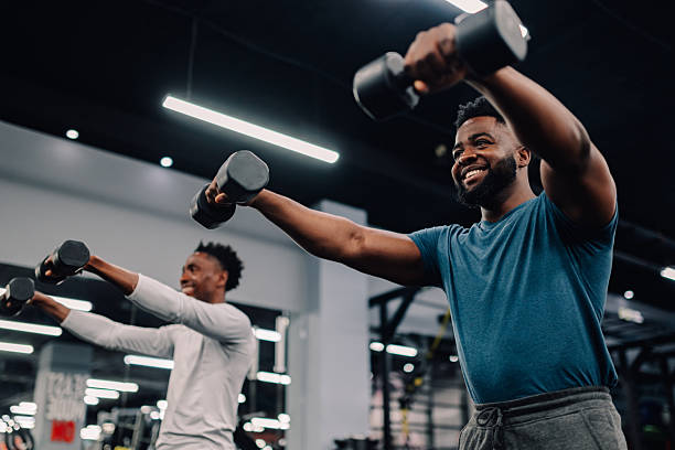 istock Two young men lifting weights in the gym 2232464411