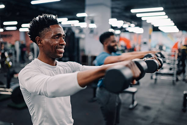 istock Two young men lifting weights in gym 2232464413