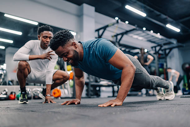 istock Personal trainer watching man doing push-ups in gym 2232464416