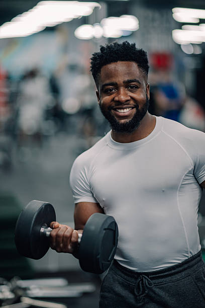 istock Young man lifting dumbbells and smiling at the gym 2232464530