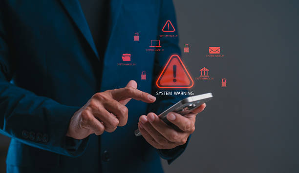 istock A person in a suit points at a smartphone displaying a system warning, surrounded by icons indicating alerts and notifications. 2232464756