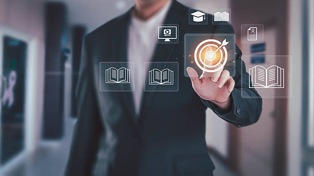 istock A businessman in a suit touches a target goal icon on a virtual screen. The interface shows education symbols like books and a graduation cap, representing e-learning and skill development concepts. 2232464885