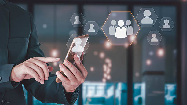 istock A businessman in a suit uses a smartphone to manage his team through a virtual interface, symbolizing human resources (HR), CRM, and business management technology. 2232465085