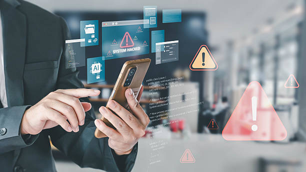 istock A businessman holds a smartphone while digital overlays show a 'SYSTEM HACKED' alert. This illustrates a cybersecurity breach, with warning icons and code, highlighting modern digital threats. 2232465089