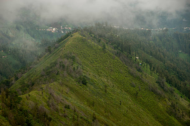 istock Misty mountain landscape with dense vegetation and hidden village 2232468155